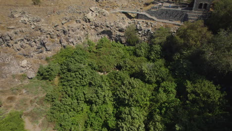 Los-Visitantes-Disfrutan-De-Las-Frías-Aguas-Del-Pico-Ein,-Un-Manantial-En-El-Sur-De-La-Zona-De-Los-Altos-Del-Golán-Y-De-Los-Restos-De-Una-Aldea-Siria,-Con-El-Kibutz-Afik-Al-Fondo.