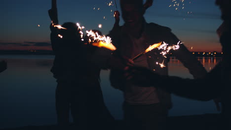 friends celebrating at sunset by the lake with sparkler