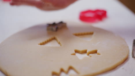 close up of a boys hand cutting out cookies for baking in dough