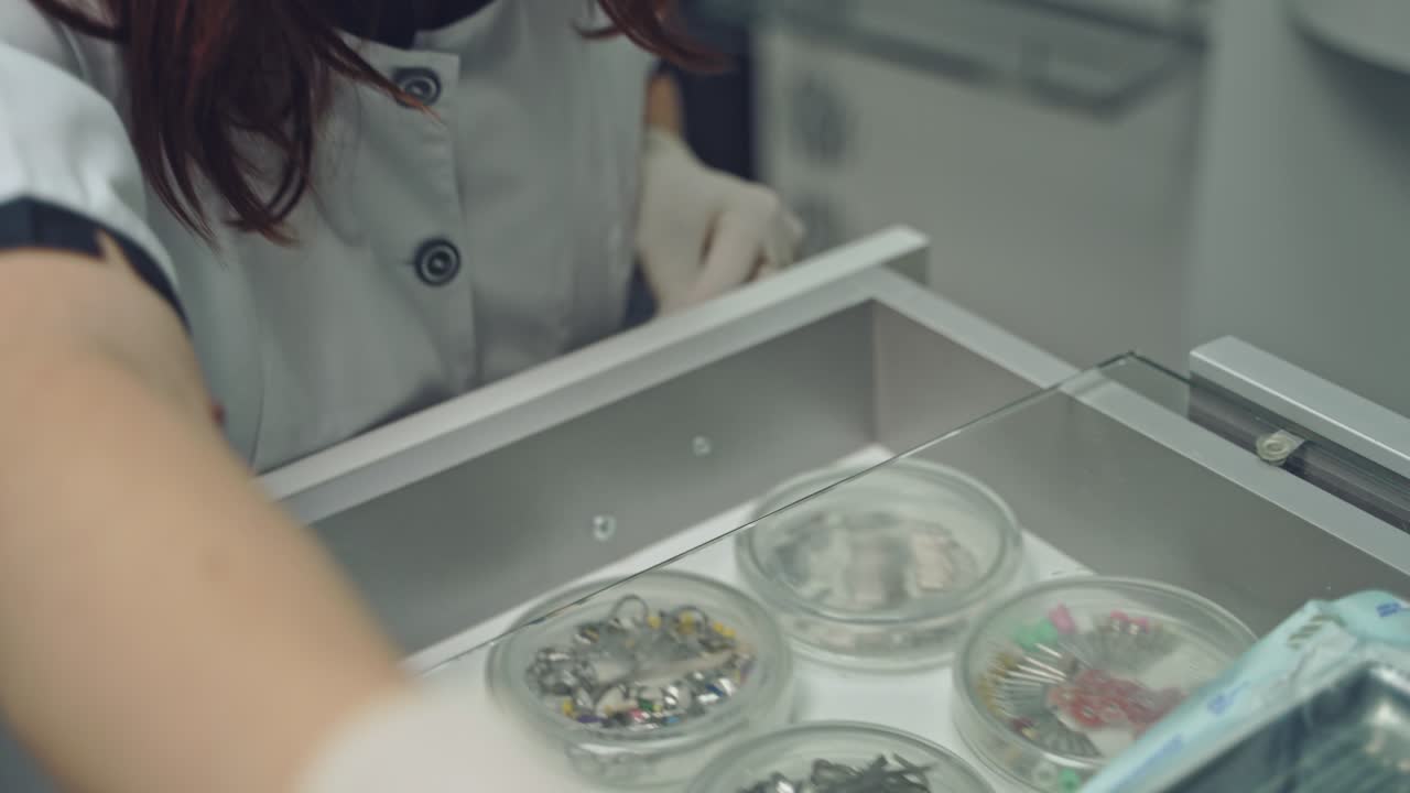 Selection of the instrument by the dentist for prosthetics on the table with a glass surface. Close-up. Modern dentistry.