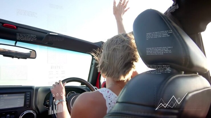 Donna che guida una decappottabile, sentendo il vento, alzando il braccio destro, con grafici HUD tecnologici sovrapposti al conducente.