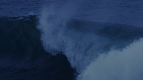 pan left along huge wave crashing into whitewash spitting foam everywhere