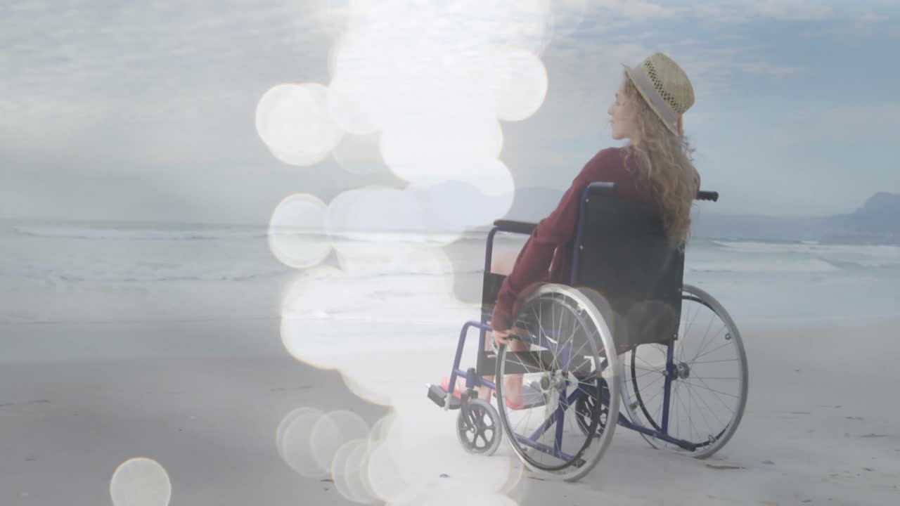 Animation of light spots over disabled cuacasian woman sitting in wheelchair at beach