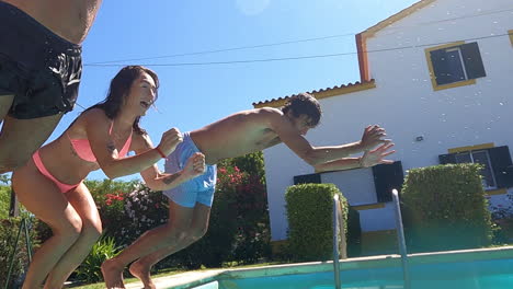 smiling men and woman in swimwear jumping in pool