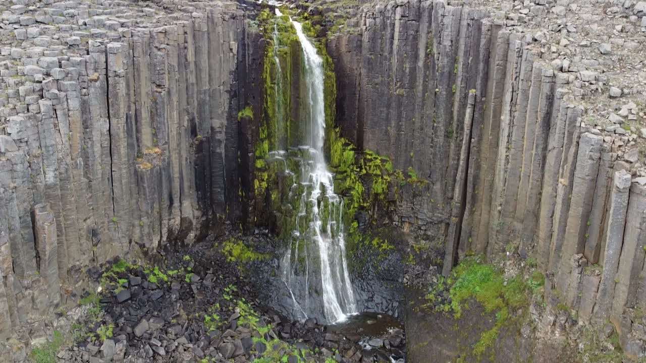 belleza de la cascada de islandia cayendo en un paisaje rocoso, vista aérea de descenso de drones