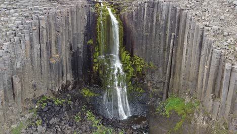 Beauty-of-Iceland-waterfall-falling-into-rocky-landscape,-aerial-drone-descend-view