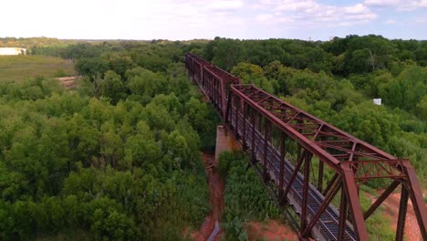 drone shot showing train tracks surrounded by trees