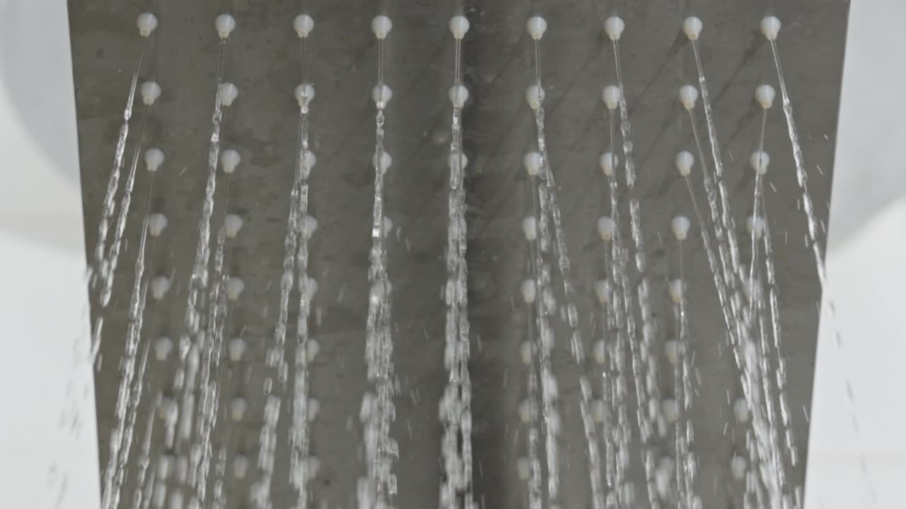 toma de primer plano chorro de agua de ducha cayendo en el flujo de apertura del baño gris blanco