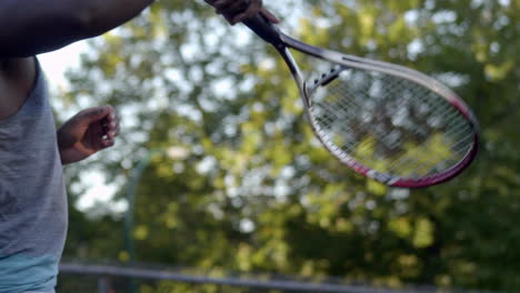 uomo nero che lancia pallina da tennis con una racchetta - primo piano slowmo