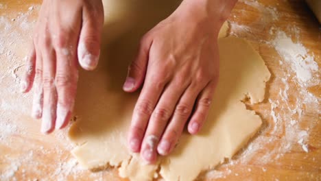 close-up-overhead-shot-of-hands-working-flour-onto-dough-baking-a-pie-crust