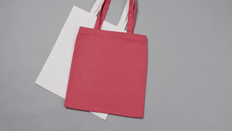 Close-up-of-white-and-red-bags-on-grey-background,-with-copy-space,-slow-motion