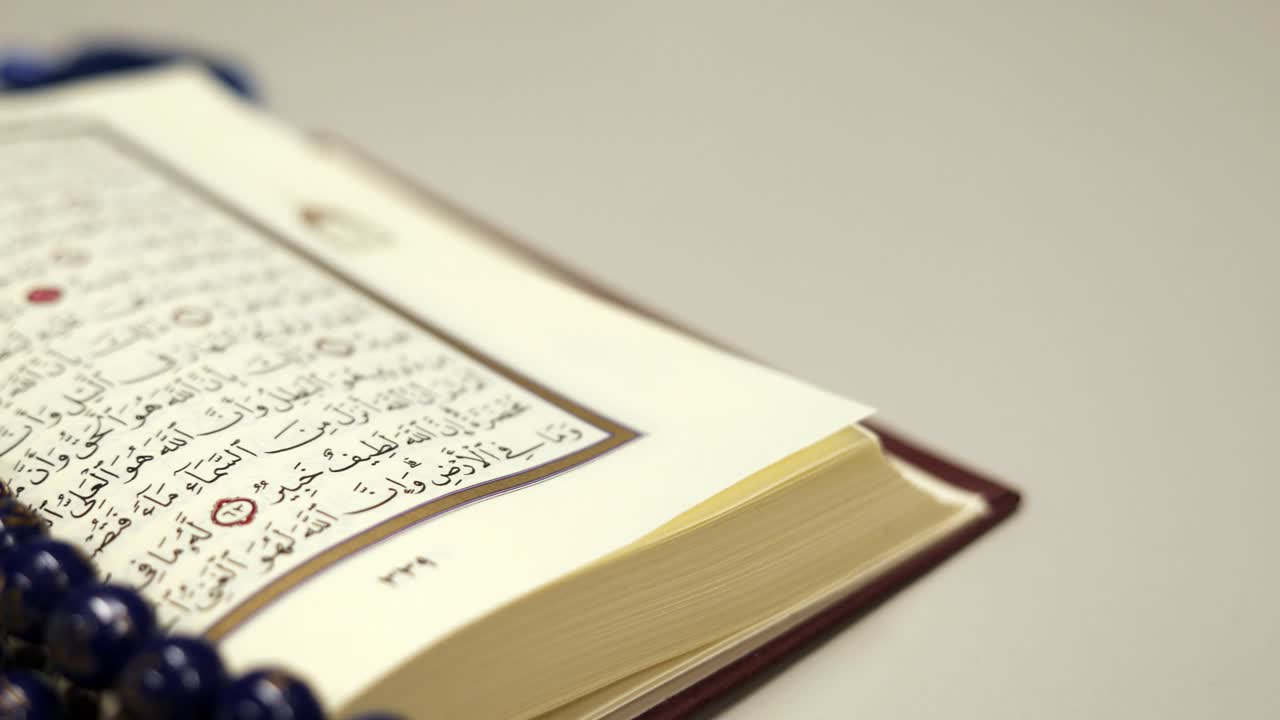imágenes de un corán tendido en una mesa con un tasbeeh, cuentas de oración, en ella. la toma se mueve de derecha a izquierda en medio círculo
