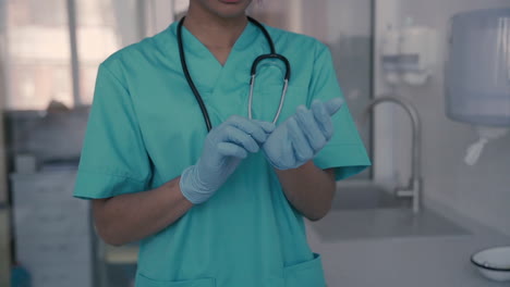 unrecognizable black female doctor puts on gloves