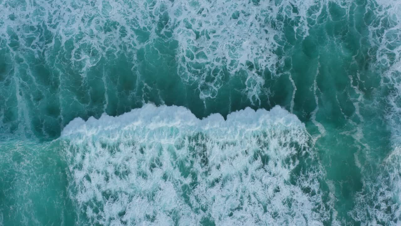 Aerial view of breaking waves on the shore, shot from done above
