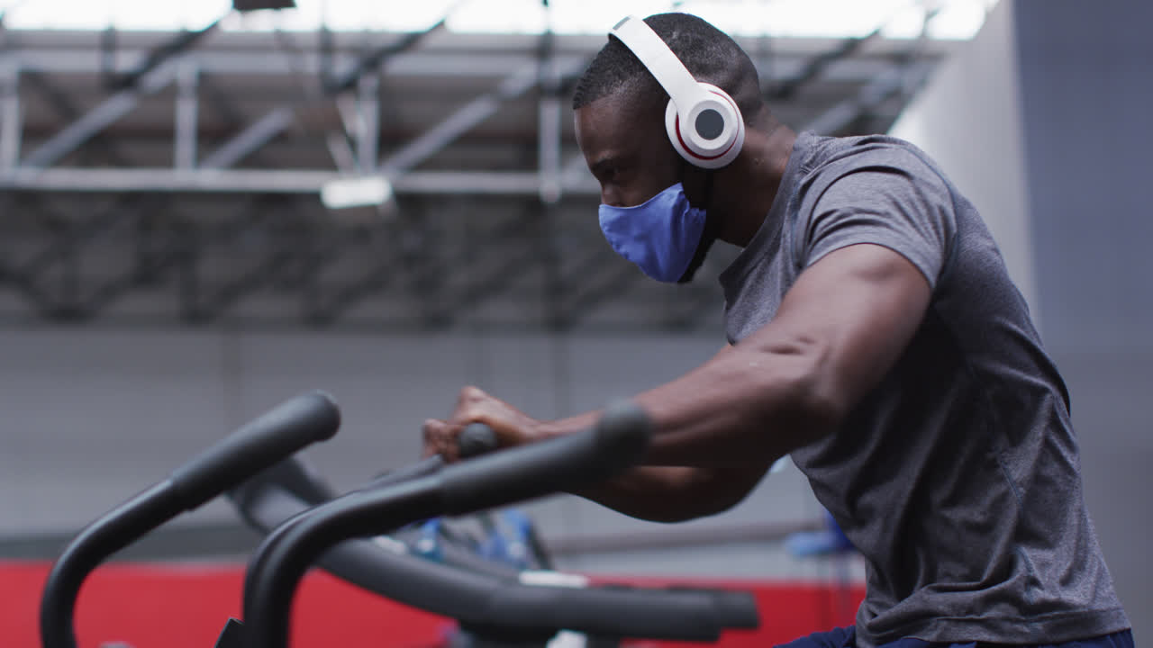 African american man wearing face mask exercising at gym