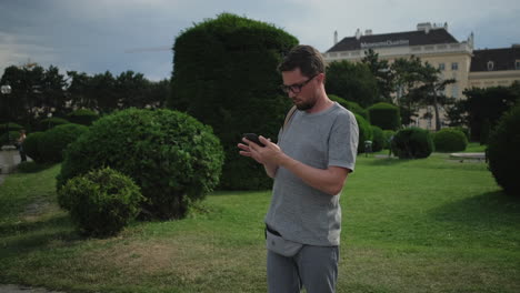 man using a smartphone in a park near a museum