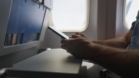 Man-typing-on-mobile-phone-during-flight-in-an-airplane