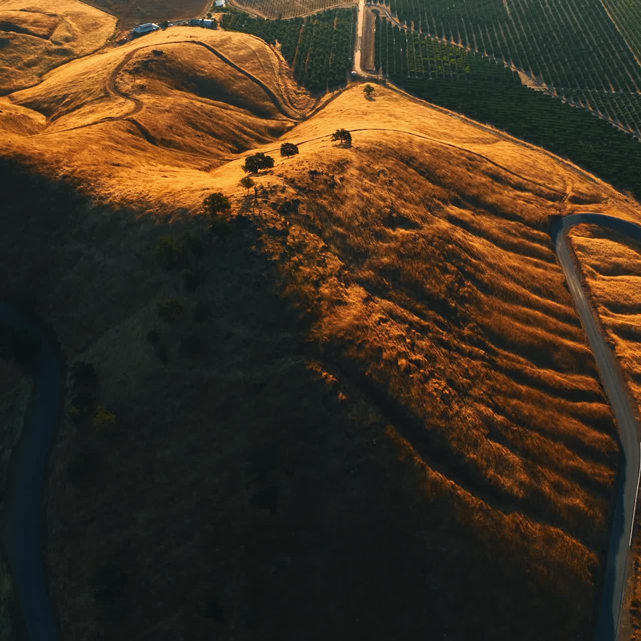 Going up over the rolled bare mount with a wavy highway on it. Green valley is at the foot of the mountains. Top view