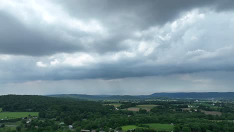 A-panning-aerial-view-of-the-lush-green-farmland-and-a-thunderstorm-forming-in-the-summer-sky