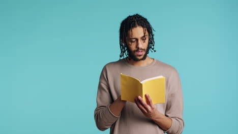 Man-reading-newly-released-hardcover-book-from-publisher,-studio-background