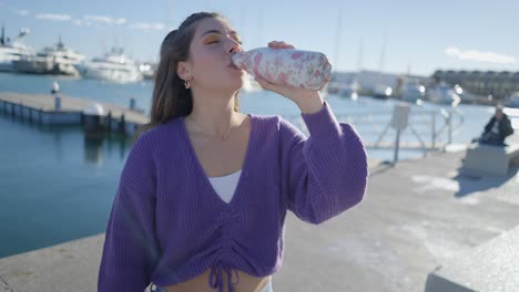young woman drinking water at the harbor