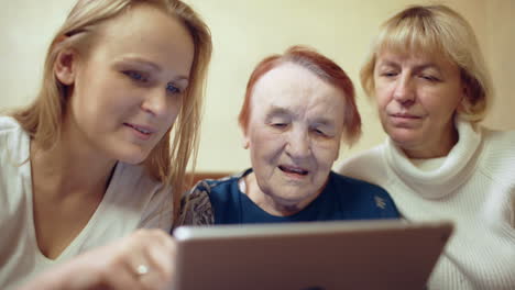 mujer con pad mostrando fotos o video a su madre y abuela