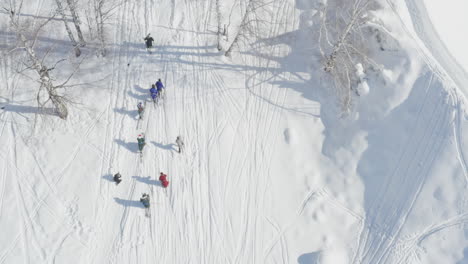 Aerial view of people walking uphill in skis on snow mountain
