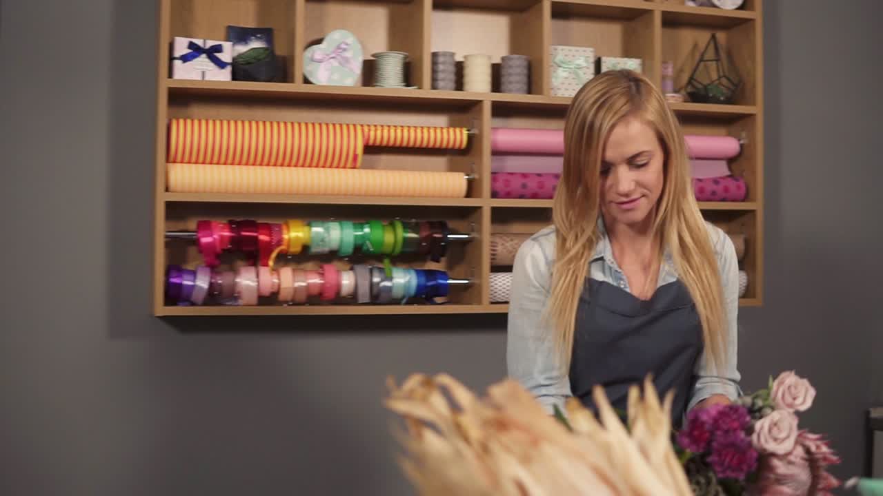 disparo en cámara lenta de una artista floral rubia profesional que arregla un hermoso ramo de bodas en un disparo de flores.