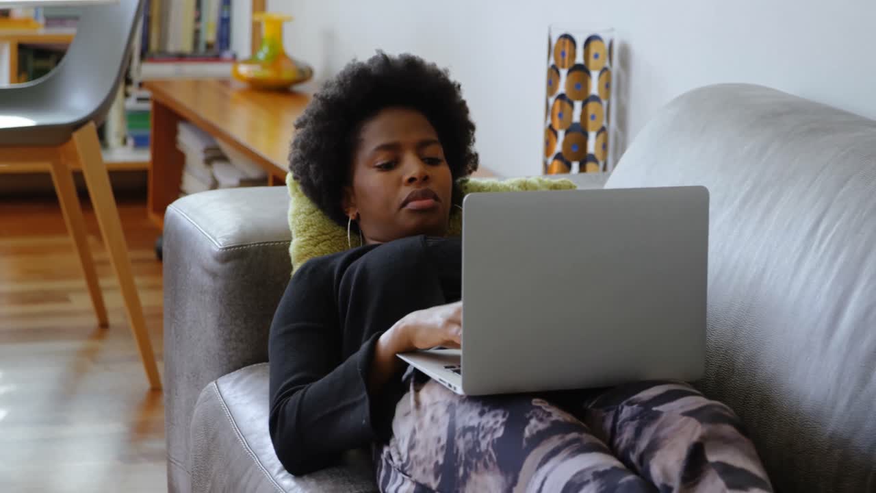 Woman using laptop on the sofa in a comfortable home 4k