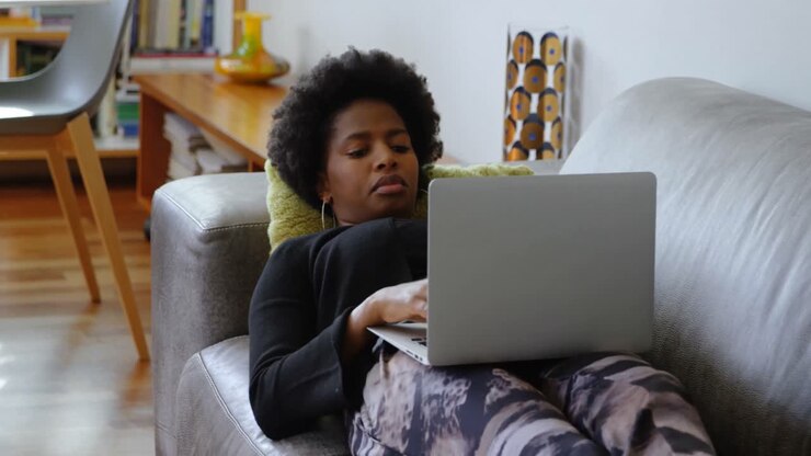 Kvinde bruger laptop på sofaen i et hyggeligt hjem 4k