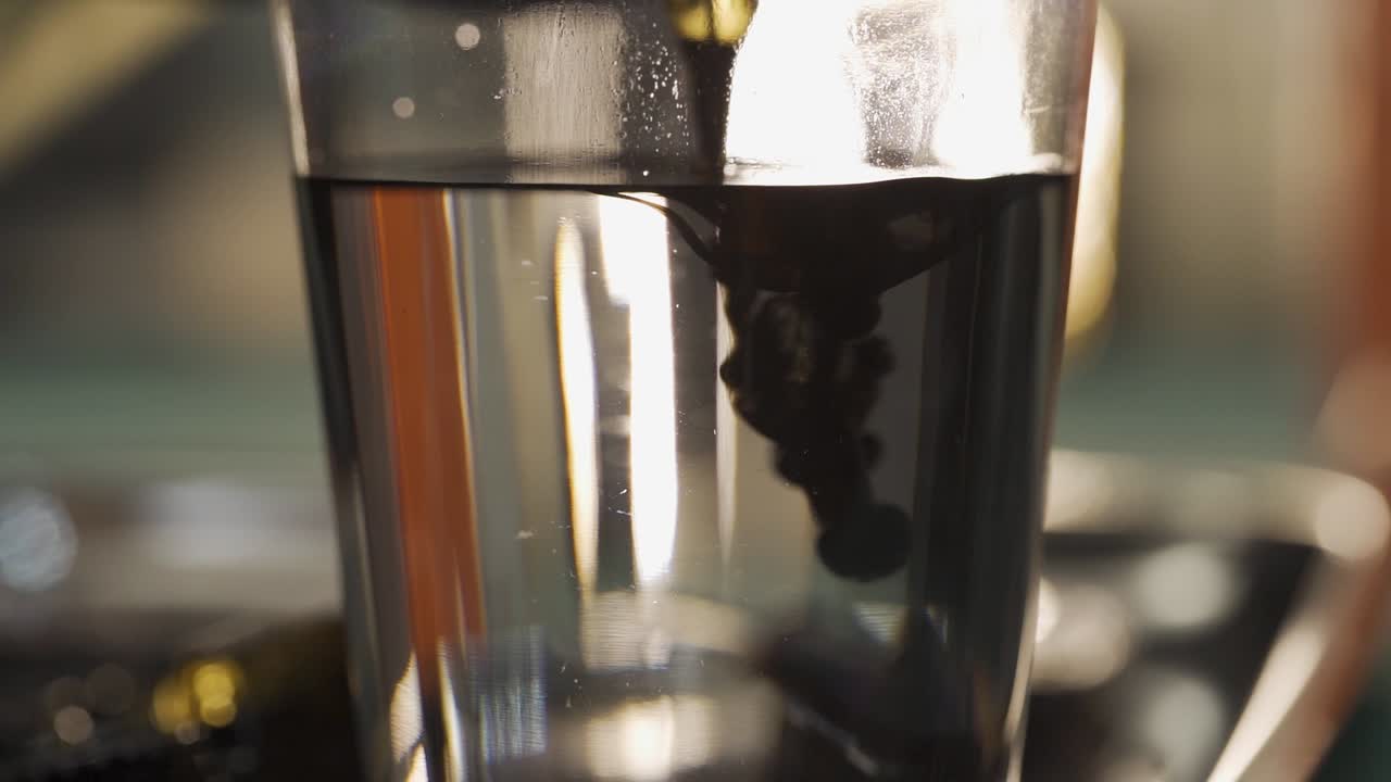 Slowmotion tattoo machine drop in water transparent glass for cleaning and make ink spread