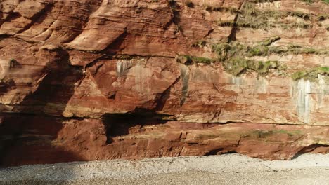 aerial tracking shot of red sandstone cliff on the jurassic coast