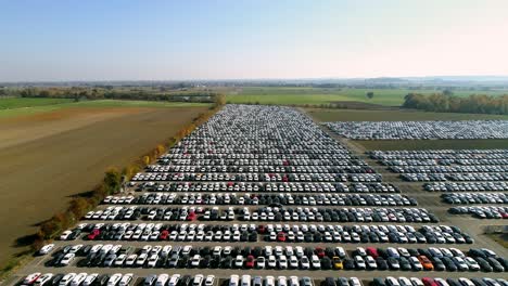 aerial footage of finished cars ready to be shipped on huge distribution center