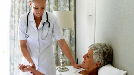 Female-doctor-checking-senior-woman-pulse-during-check-up-in-bedroom