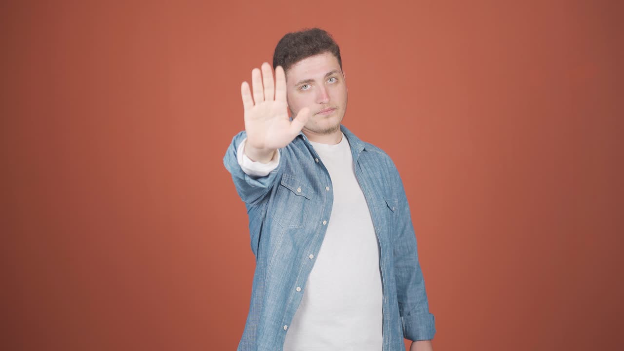 hombre haciendo una señal de parada para la cámara.