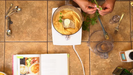 Adding-parsley-to-freshly-made-dip-still-in-the-food-processor---overhead-view