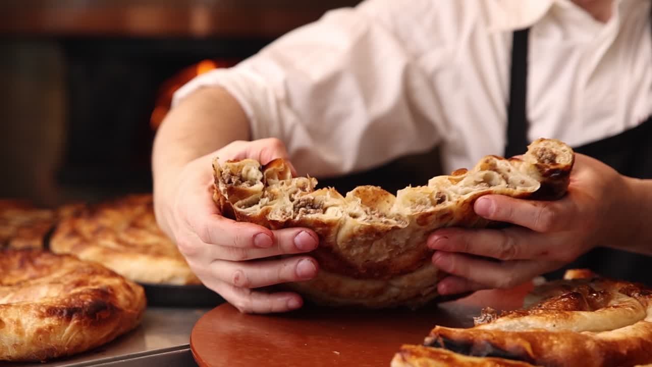 Chef's Hands Breaking Apart a Freshly Baked Meat Burek