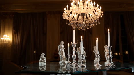 elegant room with crystal chandelier, candlelight, and classical statues
