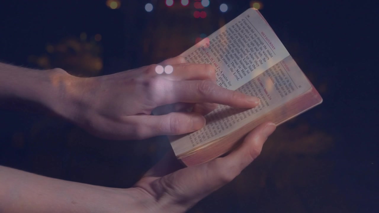 Kitap açan eller, işaret parmağı çizgileri takip ediyor, sayfaları çeviriyor, bokeh kayıyor ve okumayı gösteriyor.