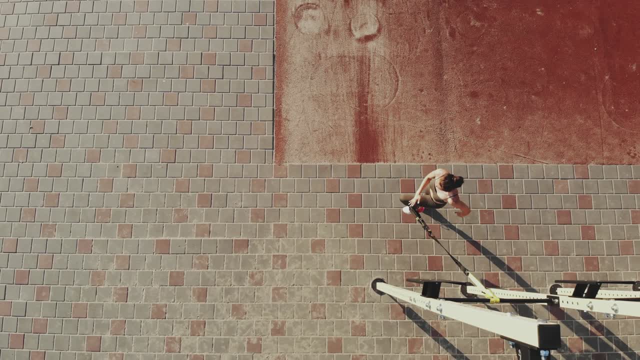 workout outdoors. suspension straps. aero top view. Athletic young woman is doing all-body resistance exercises using looped ropes TRX, on city outdoor sports ground, gym. Fitness training outdoors. healthy lifestyle concept. morning sport training in the