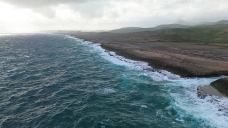 barren northside of caribbean island bombarded with strong ocean waves at drop off passing river mouth