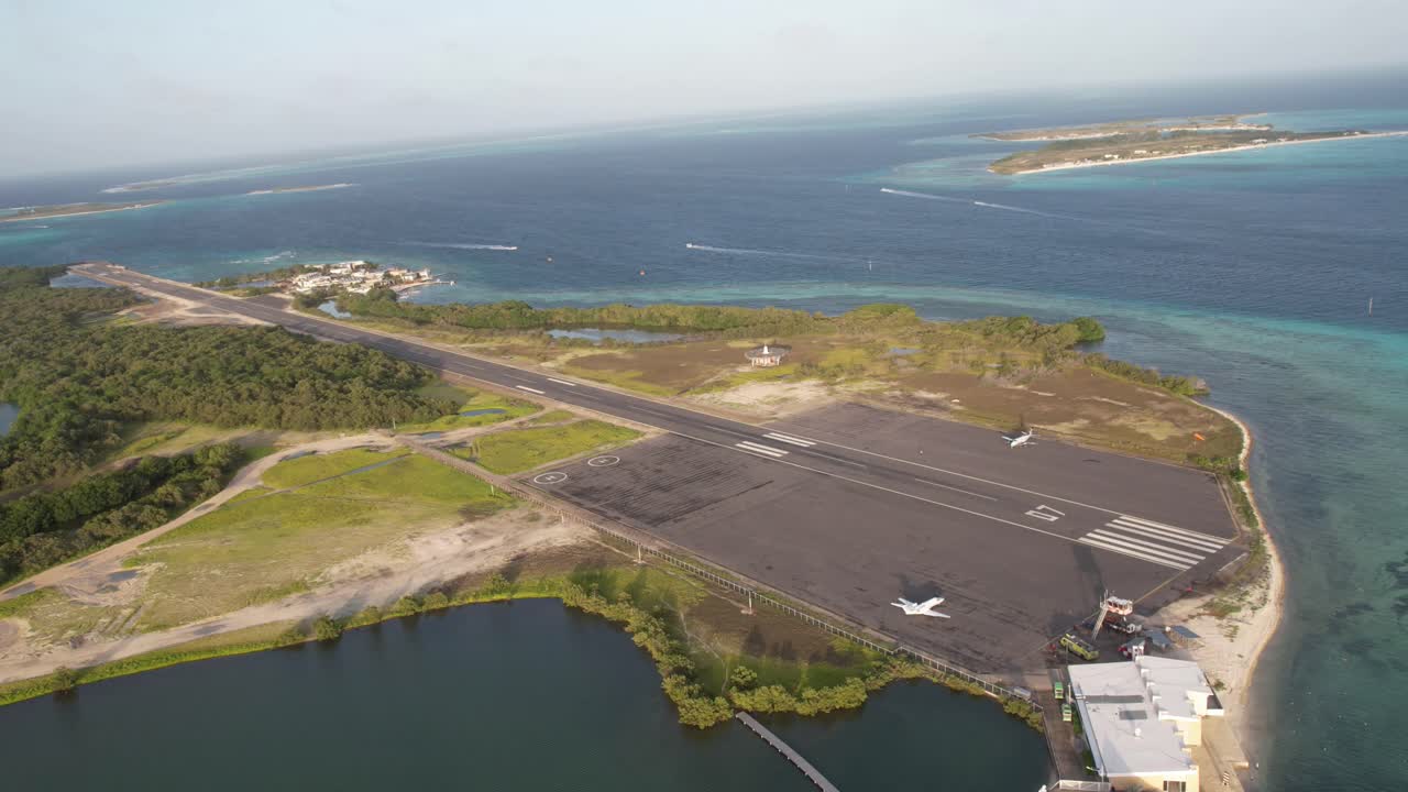 Aerial view of a coastal airport surrounded by blue sea and lush greenery