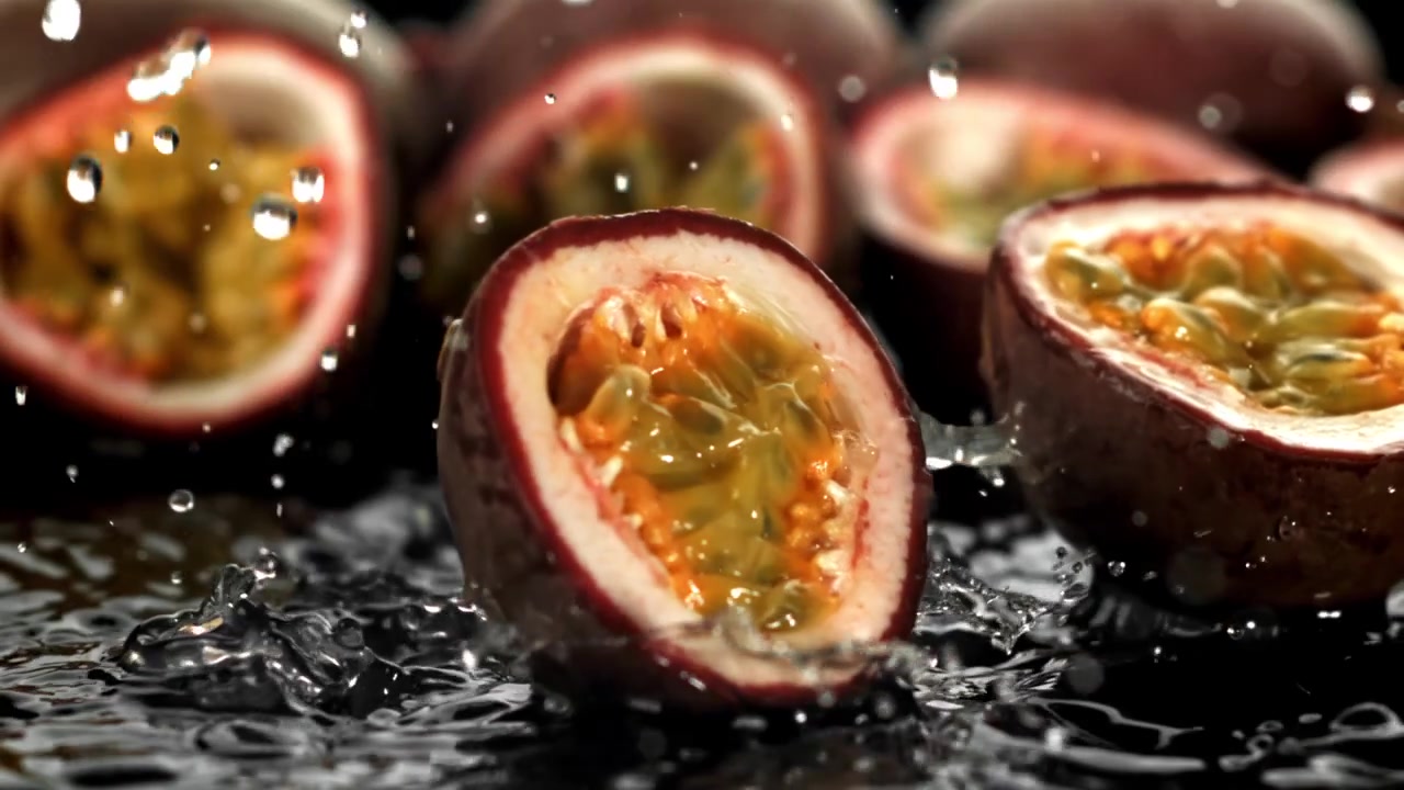 Frisk passionsfrugt falder og plasker ned i vand i slowmotion