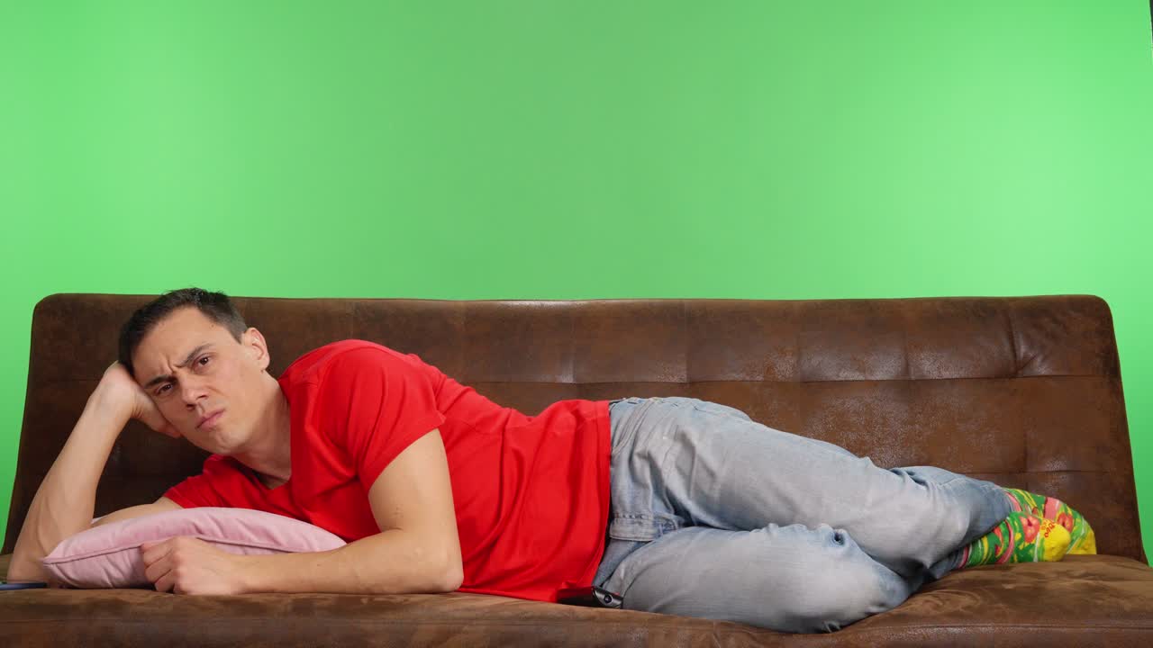 Depressed man lying on couch with remote control