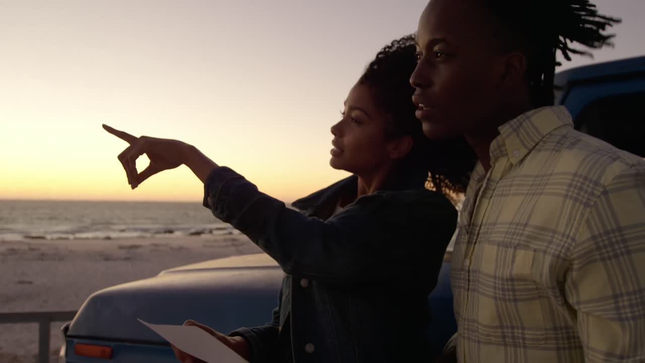 Woman pointing finger and showing something to man on beach 4k