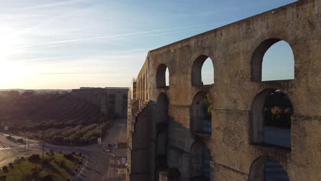 drone paralax shot of an old aqueduct in elvas, portugal, during sunset with real lens flare