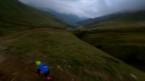 ciclista mtb extremo acelerando por el sendero de la montaña hacia el valle durante el día nublado - toma aérea de seguimiento fpv