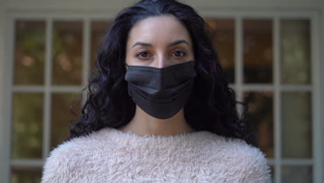 young attractive latina woman makes sure her face mask fits properly then removes it while looking at the camera