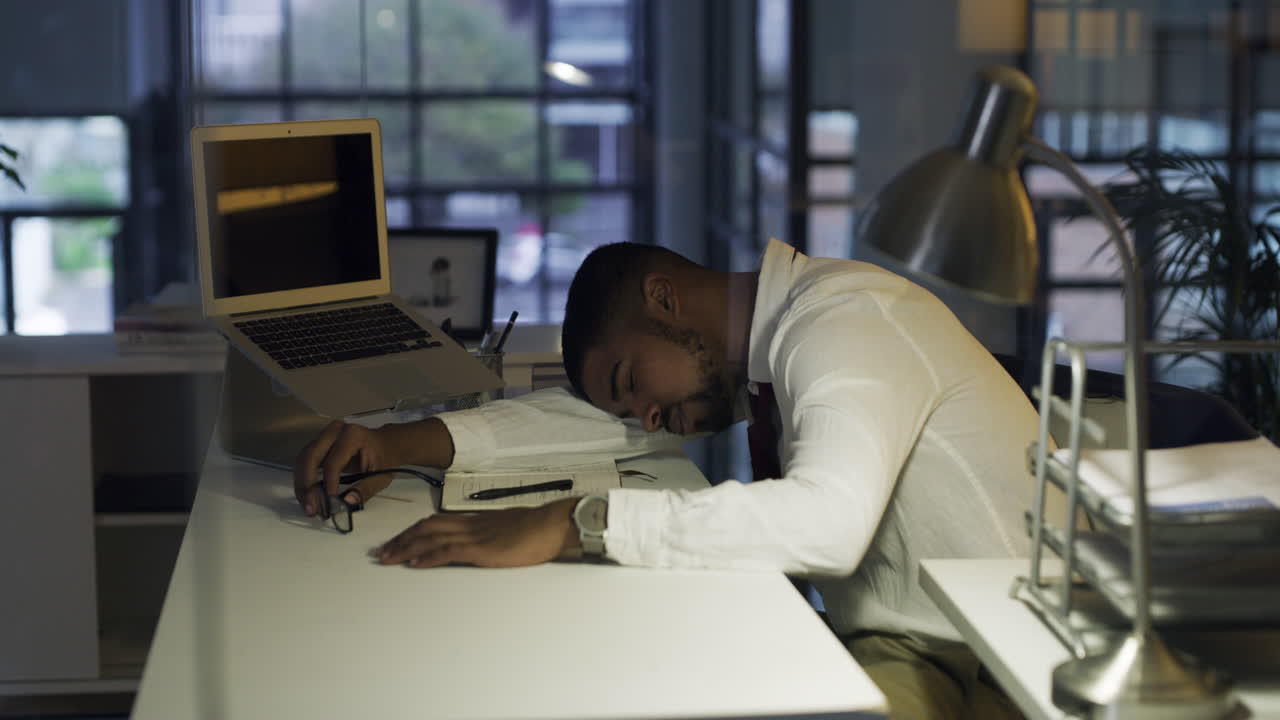 young businessman sleeping at his desk during