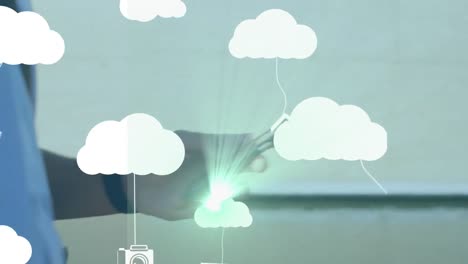animación de nubes y dispositivos tecnológicos sobre las manos de un hombre caucásico usando un teléfono inteligente.